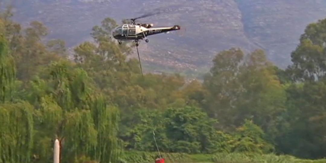 A helicopter scoops water out of a nearby dam as part of ongoing attempts to contain the Cape winelands fire.