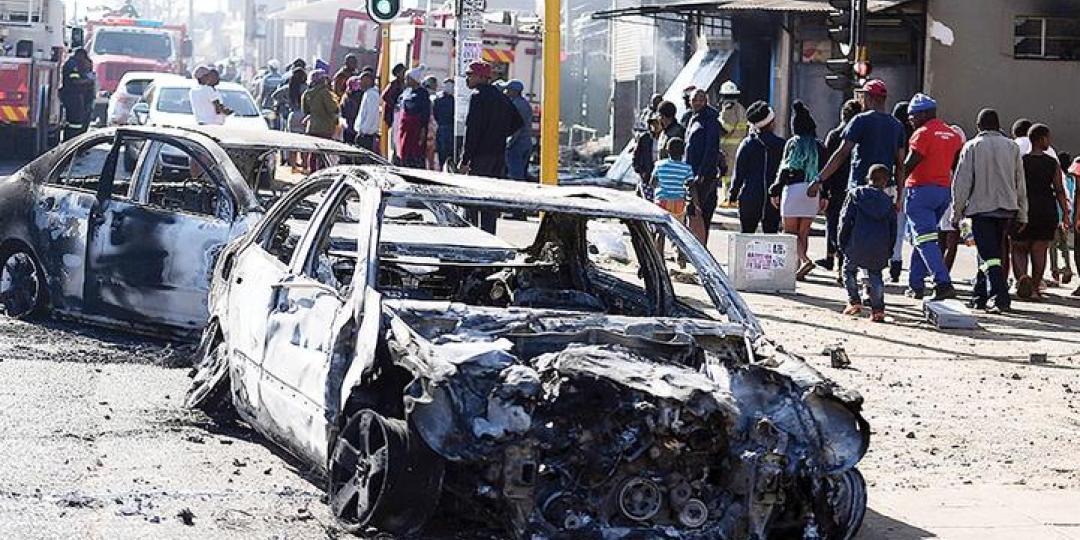 Pedestrians pass the burnt wreckages of cars destroyed in the spate of xenophobic violence.