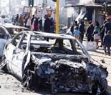 Pedestrians pass the burnt wreckages of cars destroyed in the spate of xenophobic violence.